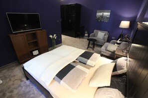 A hotel room with a bed, a TV, a desk, a chair, and a sofa. - IMCT - Ambassador Apartment (Budapest)