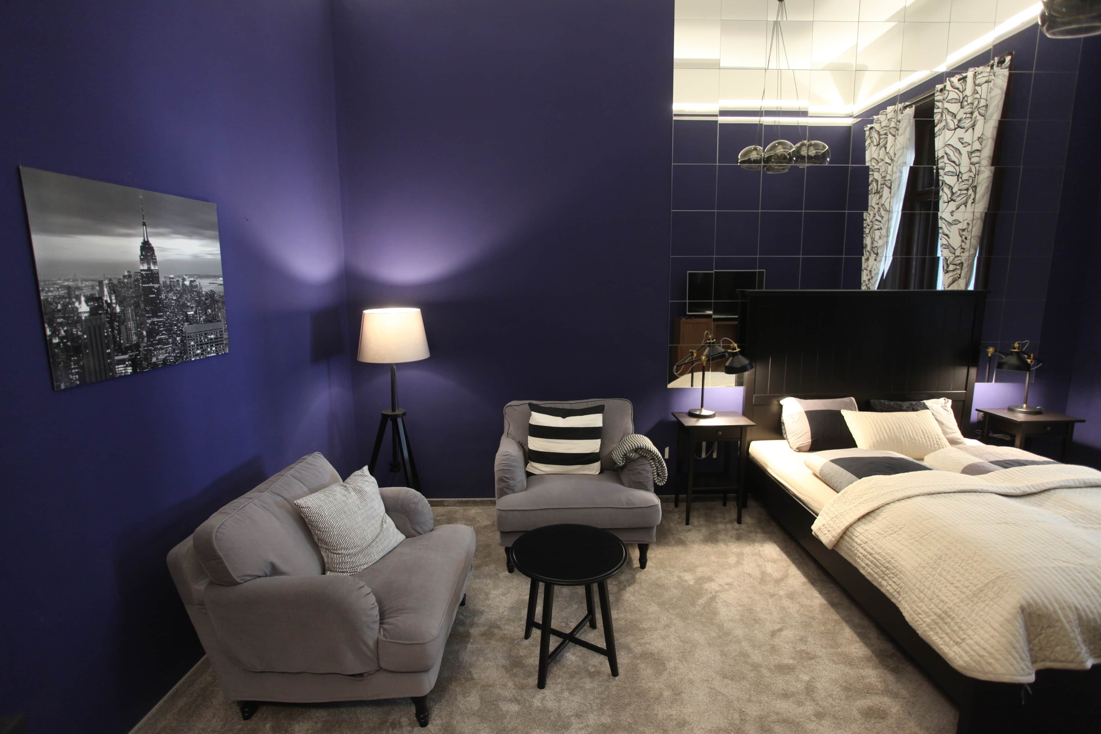 Une chambre à coucher comprenant un lit, un canapé, une chaise, une lampe et un téléviseur.