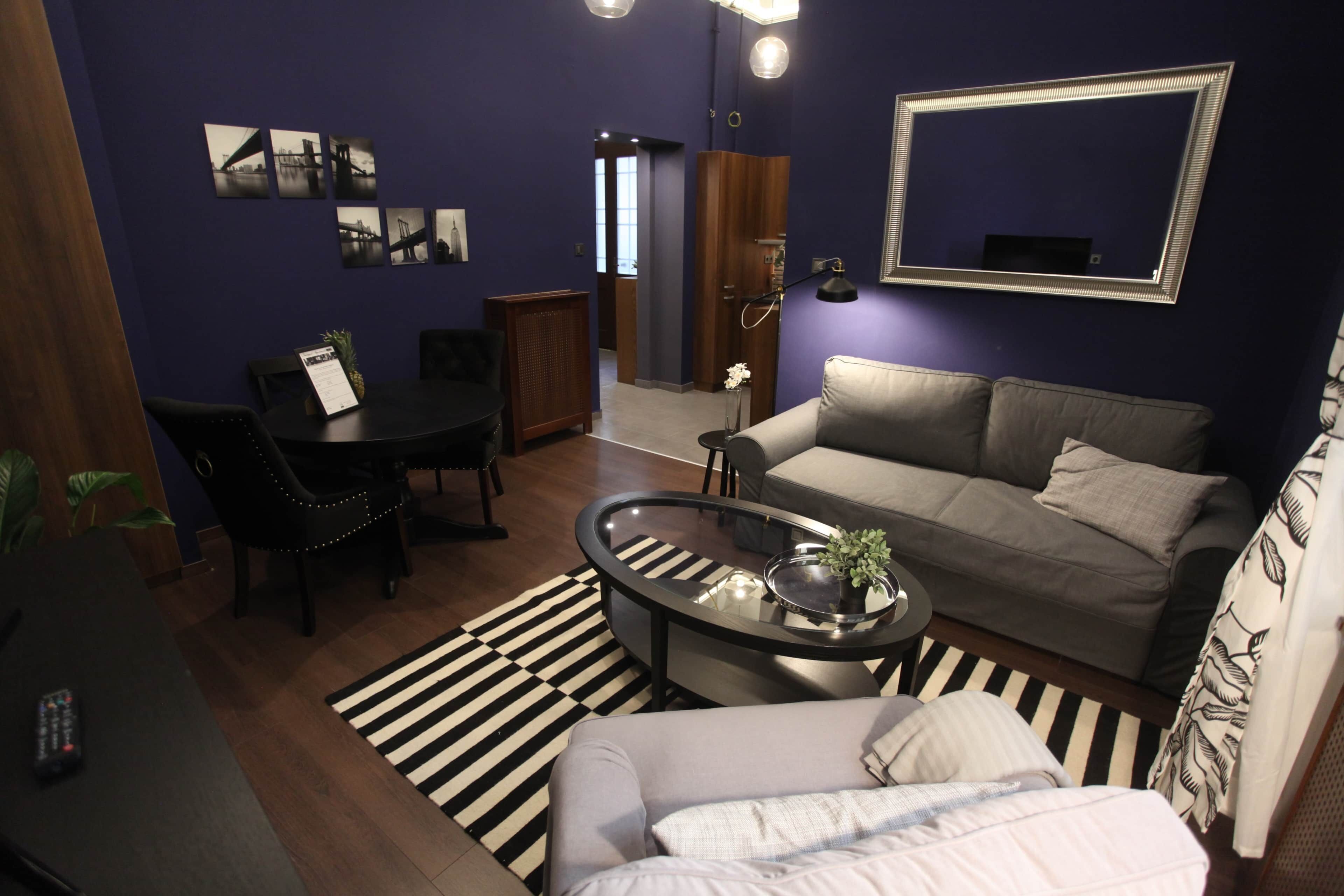 A compact living space with a sofa, a coffee table, a dining table, and a small kitchen area.