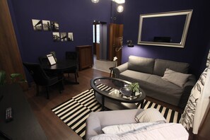 A compact living space with a sofa, a coffee table, a dining table, and a small kitchen area. - IMCT - Ambassador Apartment (Budapest)