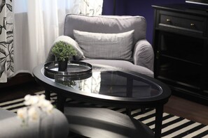A modern living room with a glass-top coffee table, a grey sofa, and a small potted plant. - IMCT - Ambassador Apartment (Budapest)