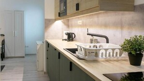 Uma cozinha moderna com micro-ondas embutido, máquina de café e pia com bandeja branca.