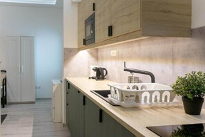 A modern kitchen with a built-in microwave, a coffee maker, and a sink with a white tray. - MidTerm - Rózsa Apartments - Jeremy B (Budapest)