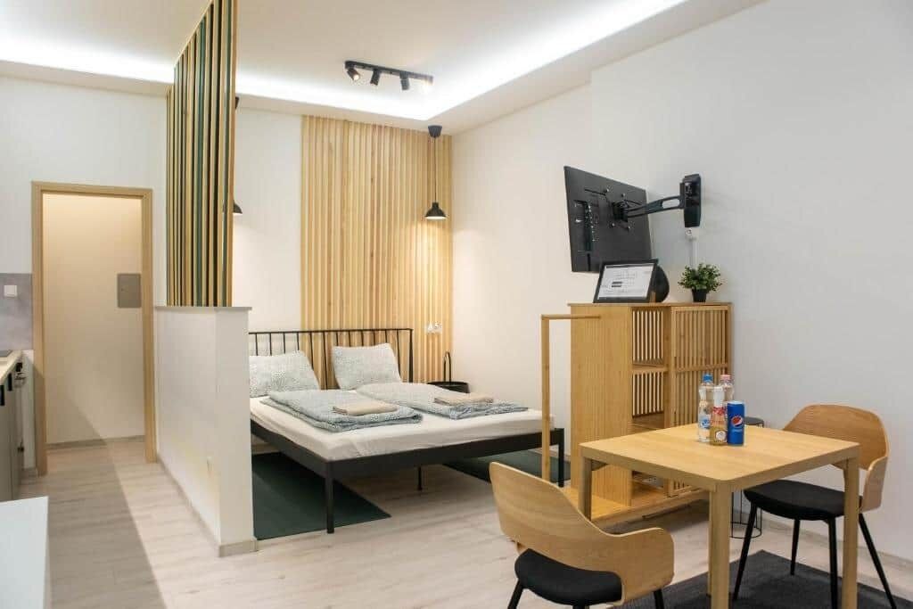 A modern bedroom with a bed, bedside table, and a desk with chairs.