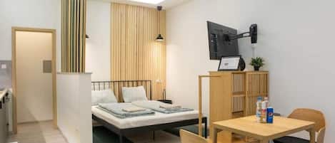 A modern bedroom with a bed, bedside table, and a desk with chairs.