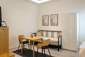 A room with a bed, a table with chairs, a TV, and artwork on the wall. - MidTerm - Rózsa Apartments - Jeremy B (Budapest)