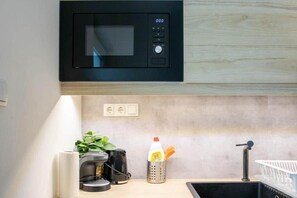 A kitchen with a microwave, a coffee machine, a sink, and a plant. - MidTerm - Rózsa Apartments - Jeremy B (Budapest)