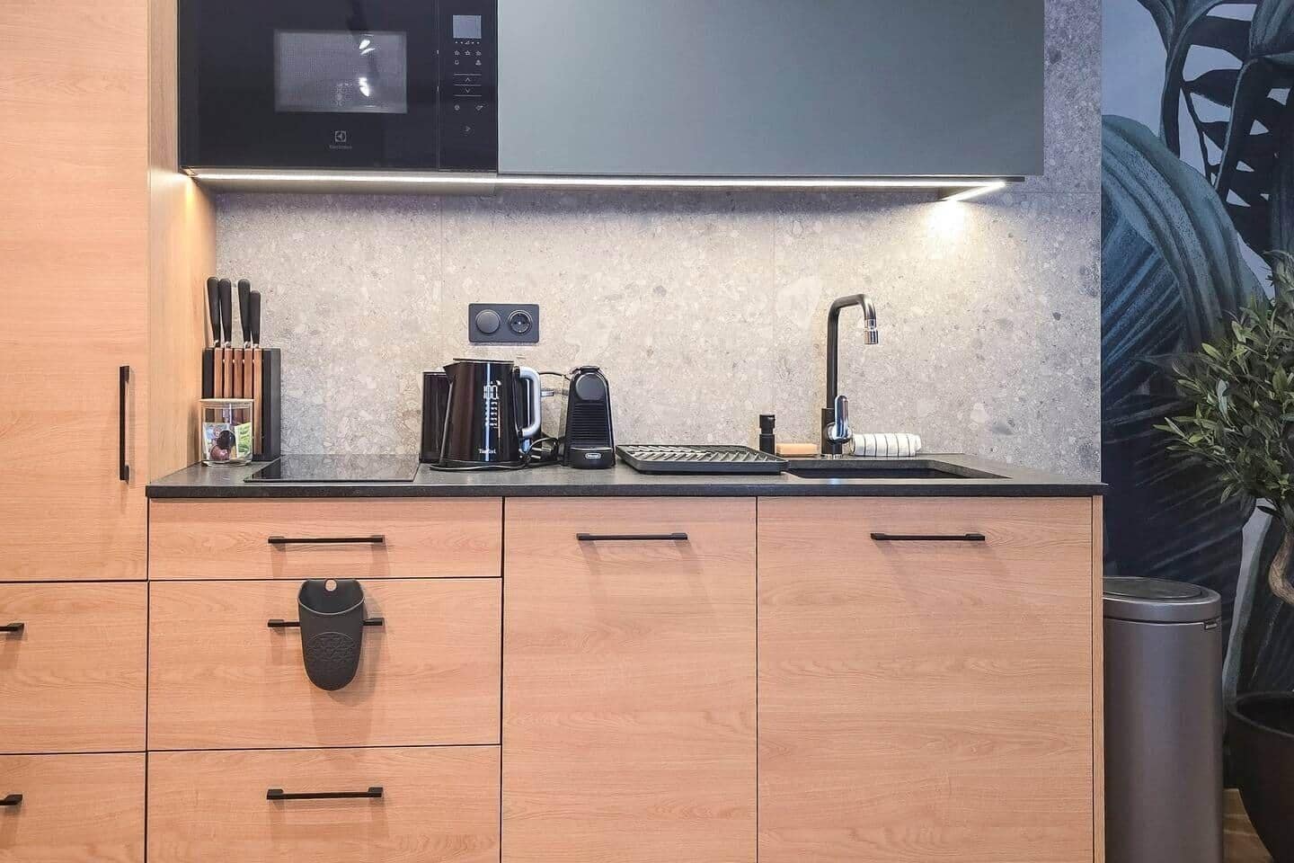 Een moderne keuken met een inbouwmagnetron, koffiezetapparaat en een spoelbak.