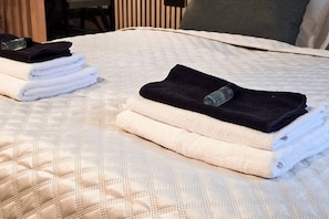 A bed with a quilted cover and neatly folded towels. - IMCT - Urban Jungle Apartments 01 (Budapest)