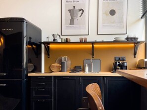 A modern kitchen with a coffee machine, a kettle, and a coffee grinder on the counter. There are framed coffee brewing method posters on the wall. - IMCT - Astoria Central Home 1 (Budapest)