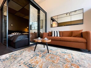 A modern living room with a sofa, a coffee table, and a large mirror on the wall. - IMCT - Astoria Central Home 1 (Budapest)