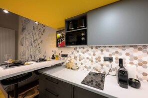 A modern kitchen with a white countertop, black cabinets, and a yellow ceiling. - Dockhouse Soho 4 (Budapest)
