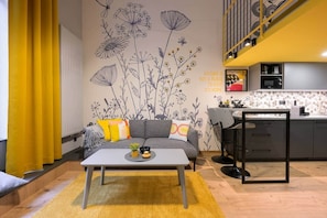 A modern living space with a sofa, coffee table, and kitchen area. - Dockhouse Soho 4 (Budapest)