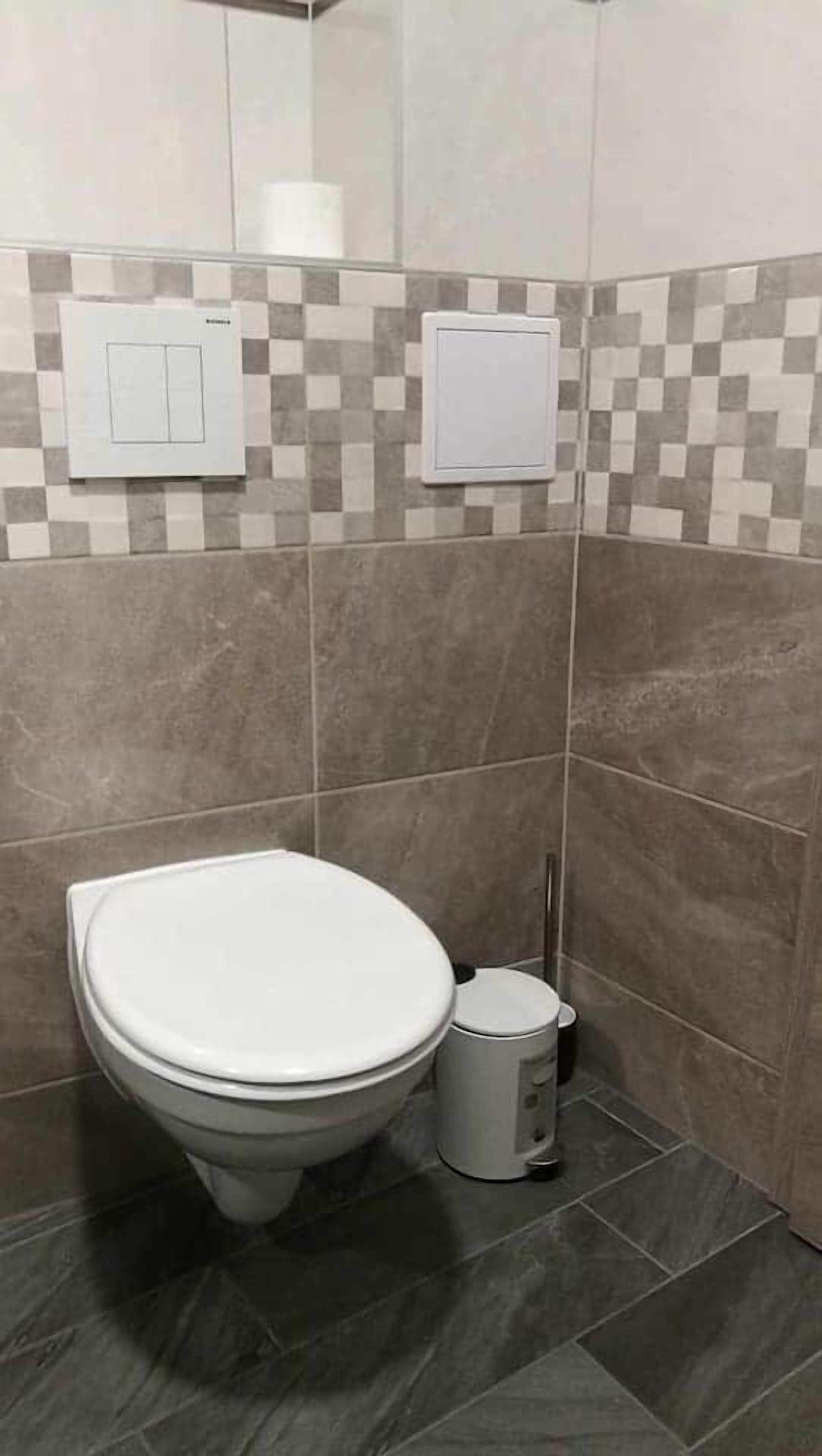 Une salle de bain équipée de toilettes, d’un bidet et d’une poubelle.