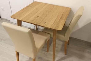 A small dining area with a square wooden table and two beige chairs. - IMCT - Beliz Apartment 2 in the City Center (Budapest)