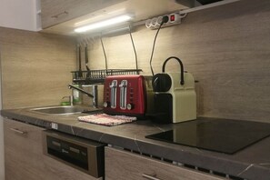 A kitchen with a built-in dishwasher, a red toaster, a kettle, and a stove. - IMCT - Beliz Apartment 2 in the City Center (Budapest)
