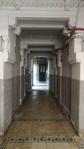 A corridor with ornate columns and a patterned floor, leading to a door at the end. - IMCT - Beliz Apartments 4 in Party District (Budapest)