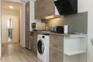 A compact kitchen with a washing machine, microwave, and toaster. - IMCT - Beliz Apartments 4 in Party District (Budapest)