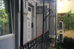 A building exterior with a white door, a black metal railing, and air conditioning units. - IMCT - Beliz Apartments 4 in Party District (Budapest)