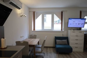 A compact living space with a dining table, a sofa, a TV, and a window with curtains. - IMCT - Beliz Apartments 4 in Party District (Budapest)