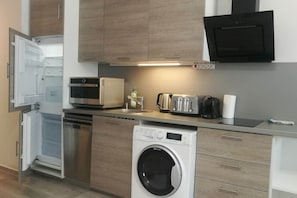 A compact kitchen with a built-in dishwasher, a microwave, a toaster, and a washing machine. - IMCT - Beliz Apartments 4 in Party District (Budapest)