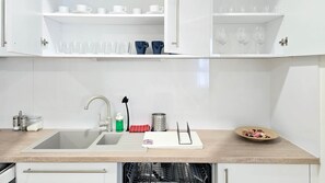 A kitchen with a sink, a dish rack, a cutting board, and a bowl of fruit. - Central Vibe Apartments 1 (Budapest)