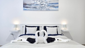 A bed with two white towels folded into swans, a white bedspread, and two bedside lamps on white nightstands. - Central Vibe Apartments 1 (Budapest)