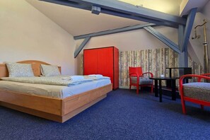 A bedroom with a wooden bed, a red wardrobe, a chair, and a small table. - IMCT - City Park Gallery Budapest (Budapest)