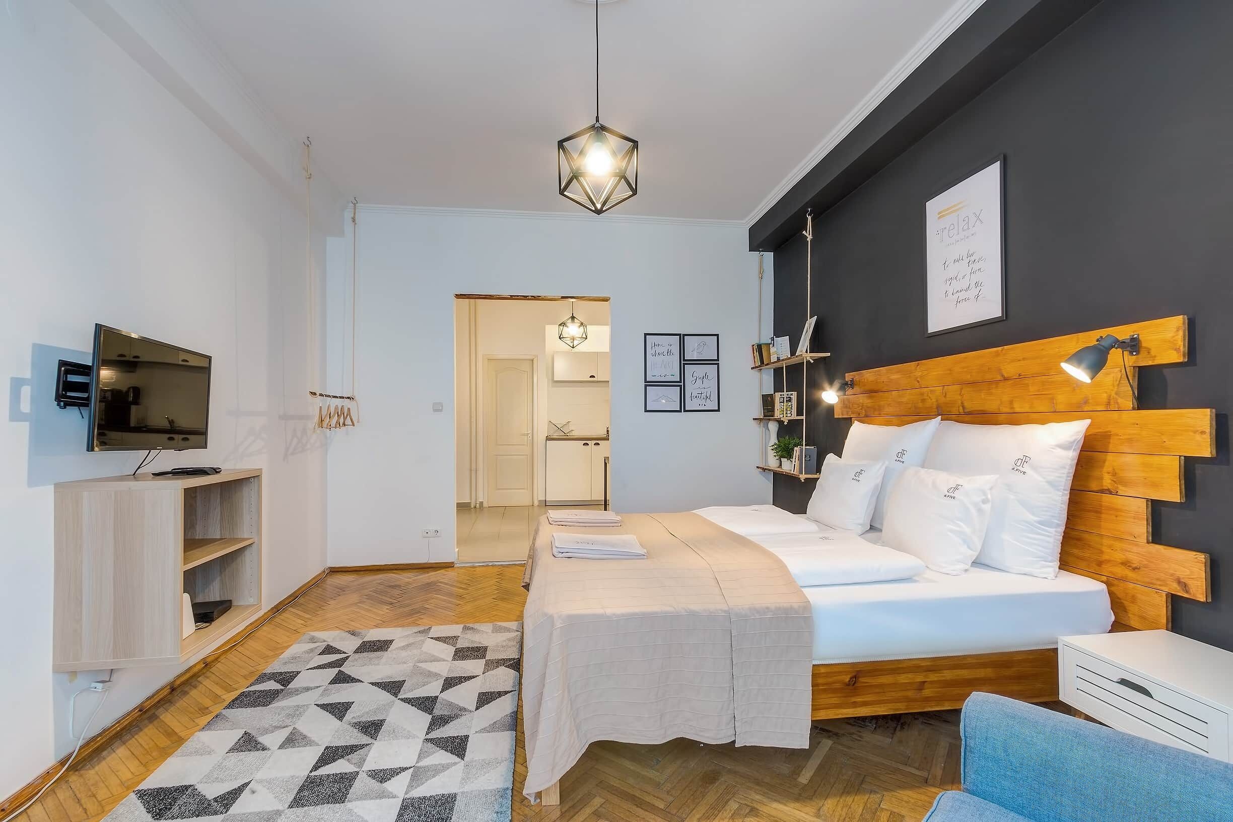 Un dormitorio moderno con cama, mesita de noche y televisor.