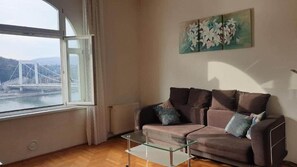 A living room with a sofa, a glass coffee table, and a painting on the wall. - IMCT - Danube View Apartment (Budapest)