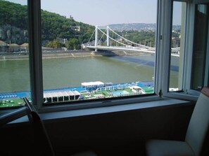 A room with a large window overlooking a river and a bridge. - IMCT - Danube View Apartment (Budapest)