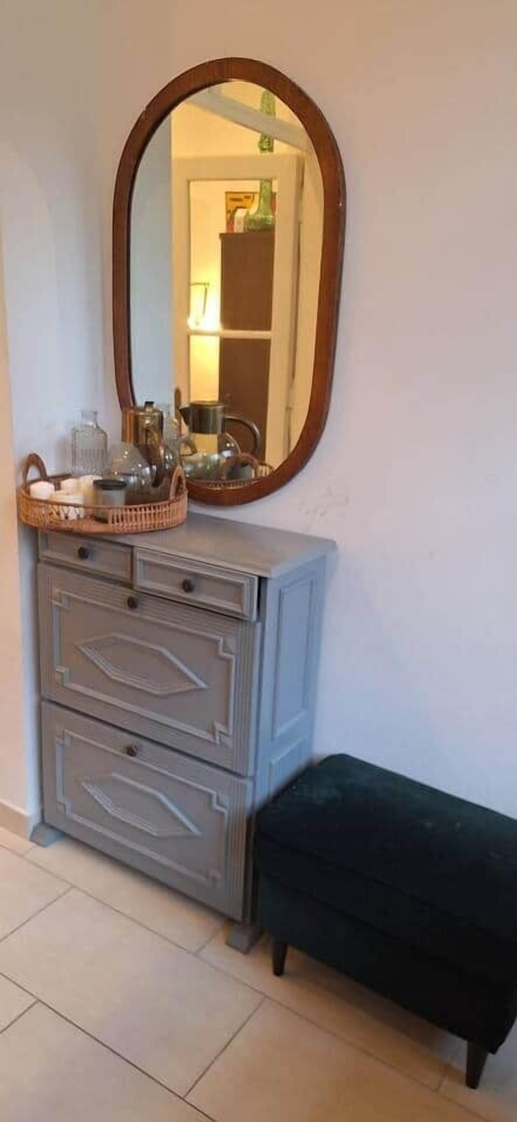 A room with a dresser, a mirror, a bench, and a basket on the dresser.