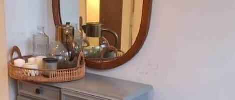 A room with a dresser, a mirror, a bench, and a basket on the dresser.