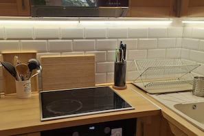 Eine Küche mit einer Holzausziehtafel, einem Tablet, einem Besteckhalter und einem Metallregal.