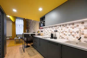 A modern kitchen with a white countertop, dark cabinets, and a hexagonal tile backsplash. - IMCT - Dockhouse Soho 2 (Budapest)