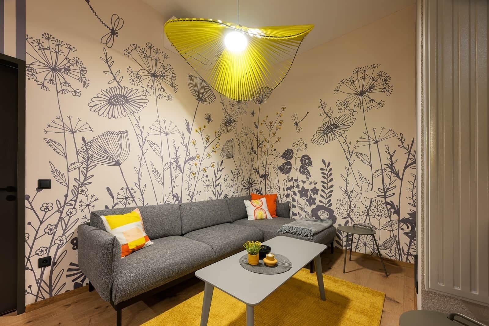 A modern living room with a grey sofa, a small table, and a yellow rug.