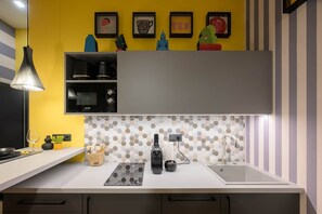 A kitchen with a microwave, a sink, and a countertop with a hexagonal tile backsplash. - IMCT - Dockhouse Soho 1 (Budapest)