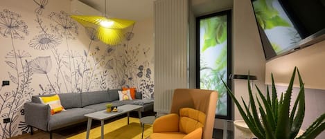 A modern living room with a sofa, armchair, coffee table, and a potted plant.