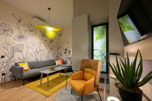 A modern living room with a sofa, armchair, coffee table, and a potted plant. - IMCT - Dockhouse Soho 1 (Budapest)