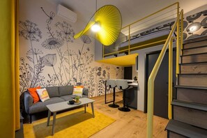 A compact living space with a sofa, coffee table, and a staircase leading to an upper level. - IMCT - Dockhouse Soho 3 (Budapest)