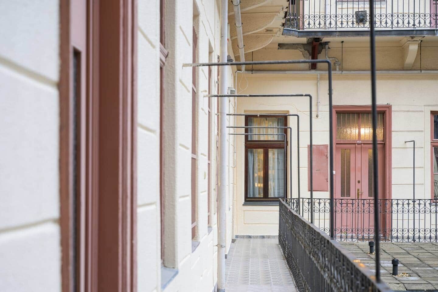 A building facade with a balcony, a window with a curtain, and a door with a shutter.