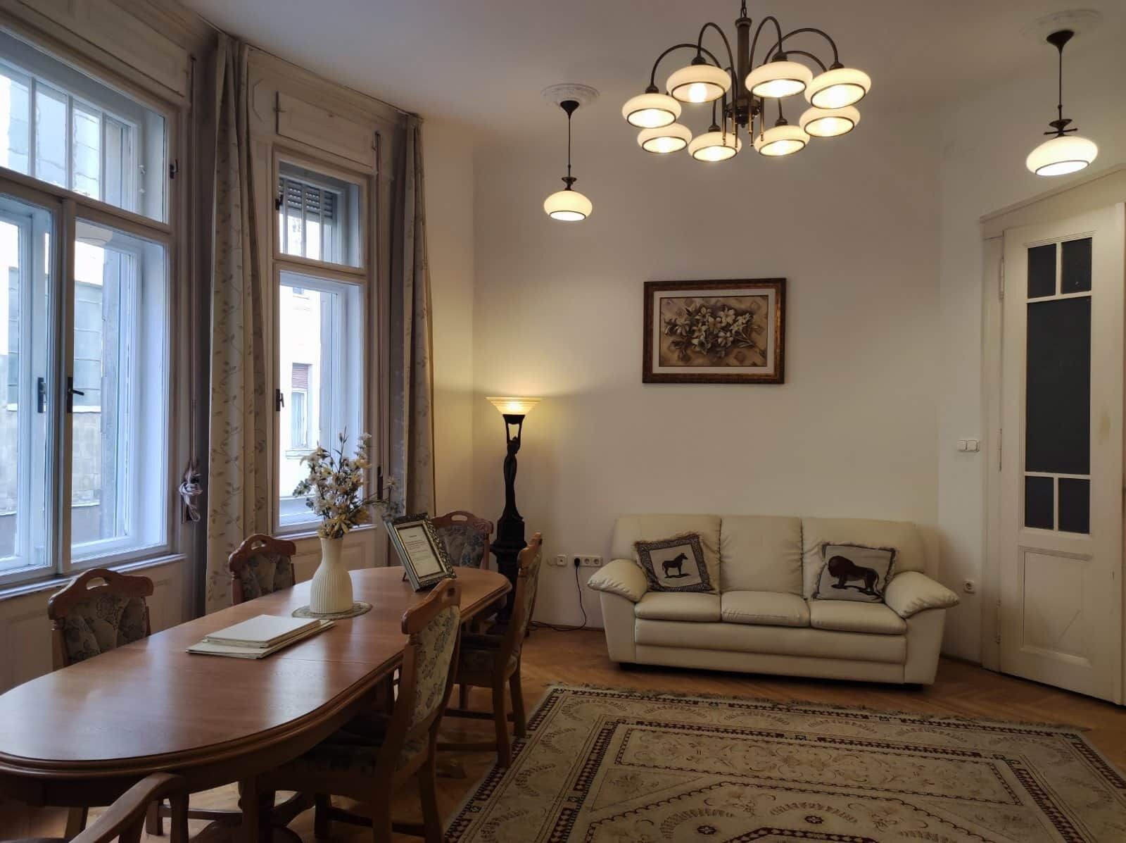 Une pièce comprenant une table à manger, des chaises, un canapé, un lustre et un tapis.