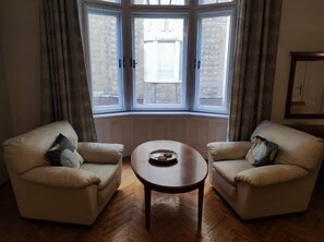 A room with two armchairs, a small round table, and a bay window with curtains. - IMCT - Elegance in the Heart (Budapest)