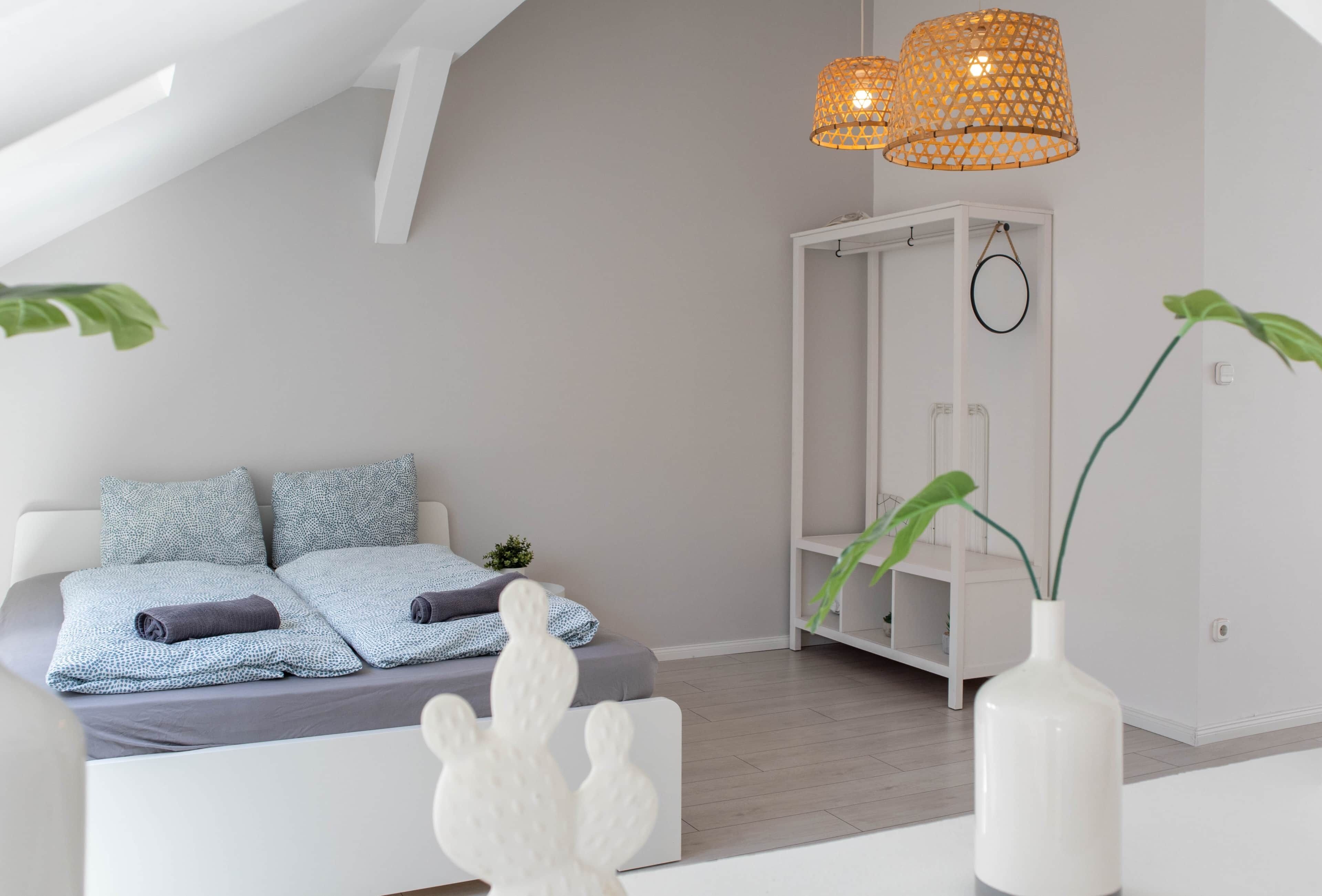 Een moderne slaapkamer met een bed, een witte garderobe en een hanglamp.