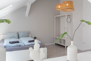 Une chambre à coucher moderne avec un lit, une armoire blanche et un luminaire suspendu.