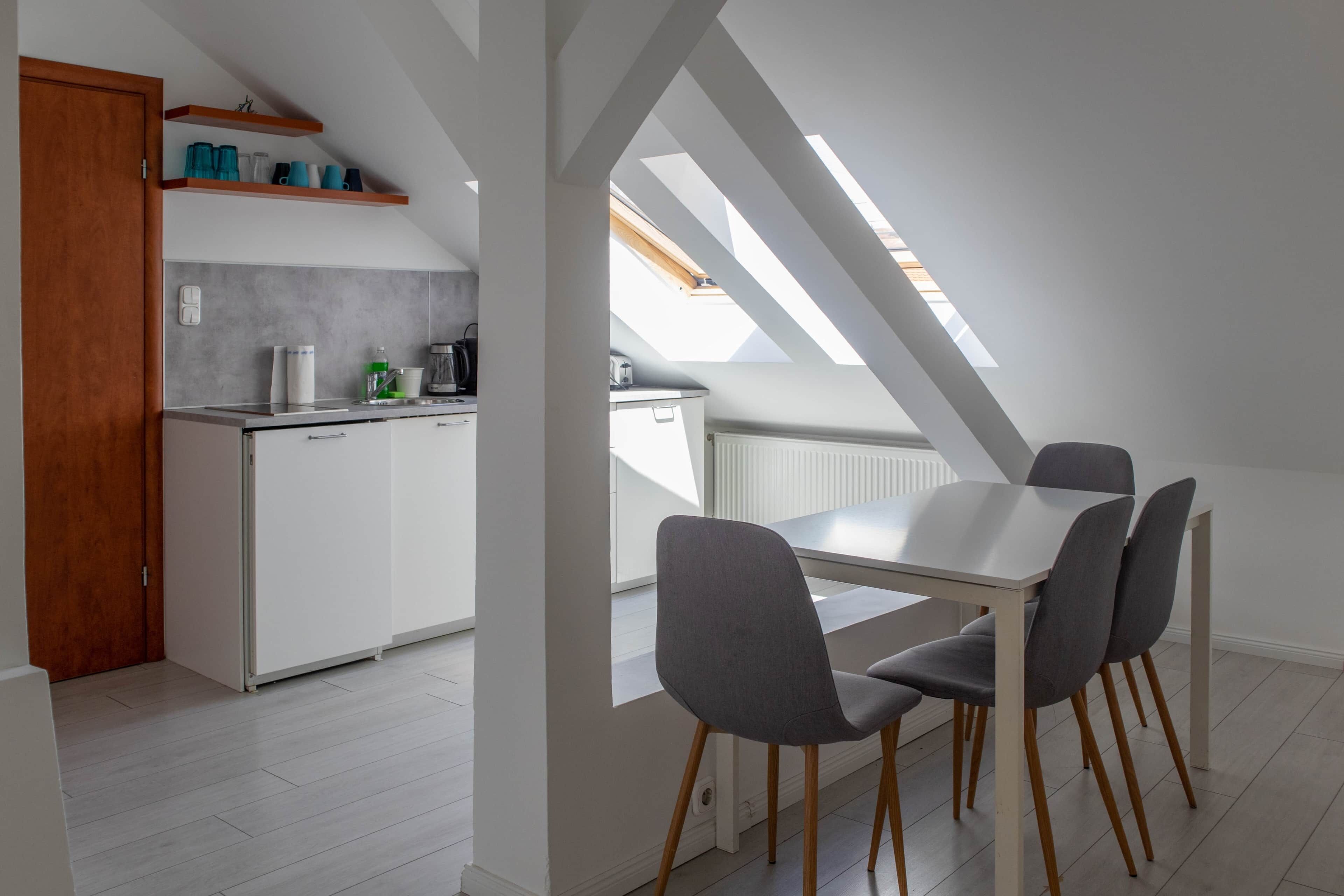 Een moderne keuken met witte kasten, een aanrecht en een dakraam erboven.