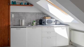 Een moderne keuken met een dakraam, witte kastjes en een inbouwmagnetron.