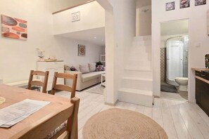 A modern interior with a dining area, a sofa, and a staircase leading to a bathroom. - IMCT - MSpirit Apartman B Budapest (Budapest)