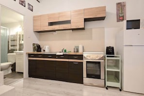 Eine kompakte Küche mit Herd, Backofen und Mikrowelle, einem kleinen Kühlschrank und einer Vitrine.