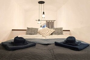 A bedroom with a bed, pillows, a quilted blanket, and a hanging light fixture. - IMCT - MSpirit Apartman B Budapest (Budapest)